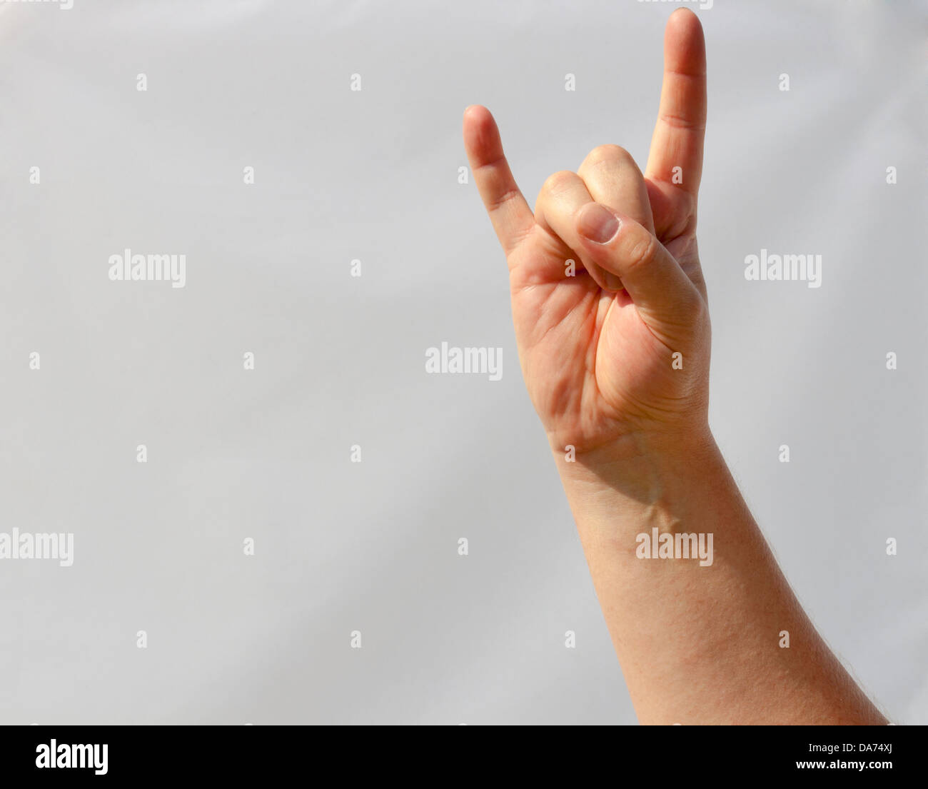 man hand shows the gesture heavy metal sign closeup. background is not clipped out, it's really white. Stock Photo