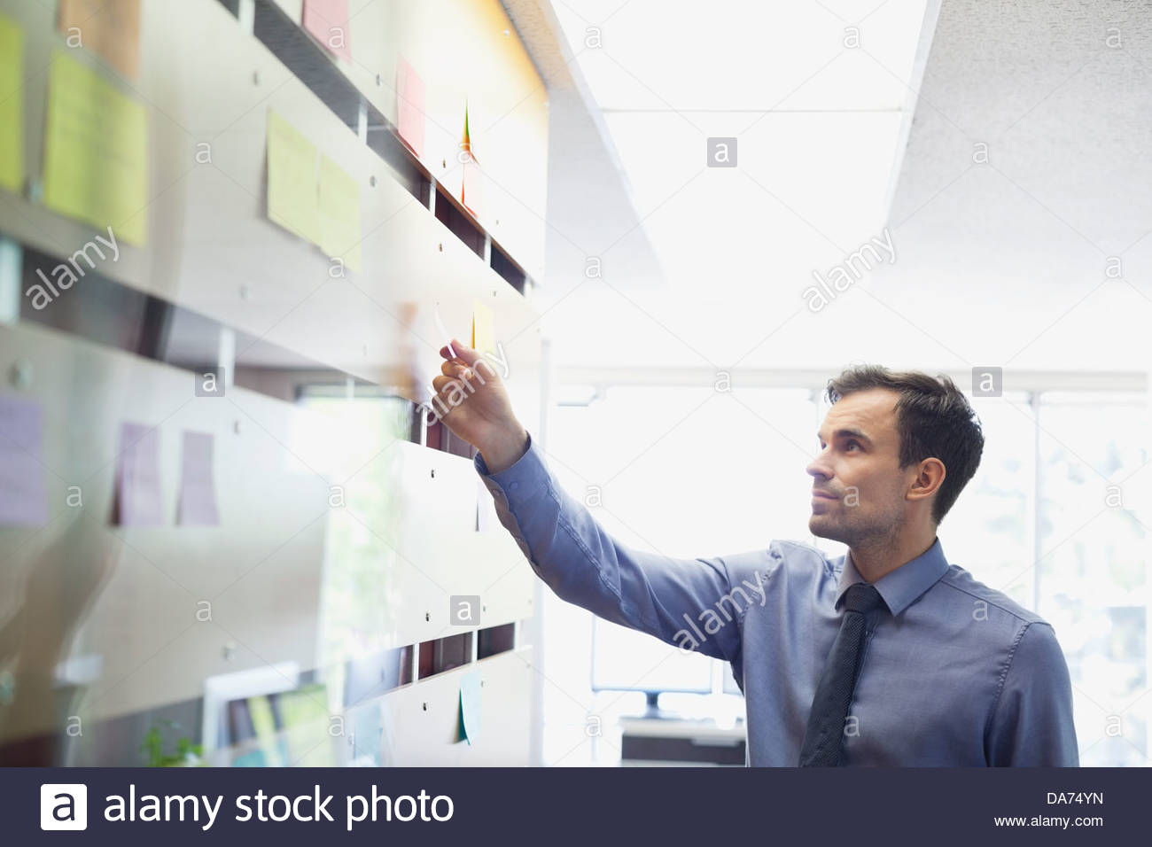 Businessman putting sticky note on wall Stock Photo