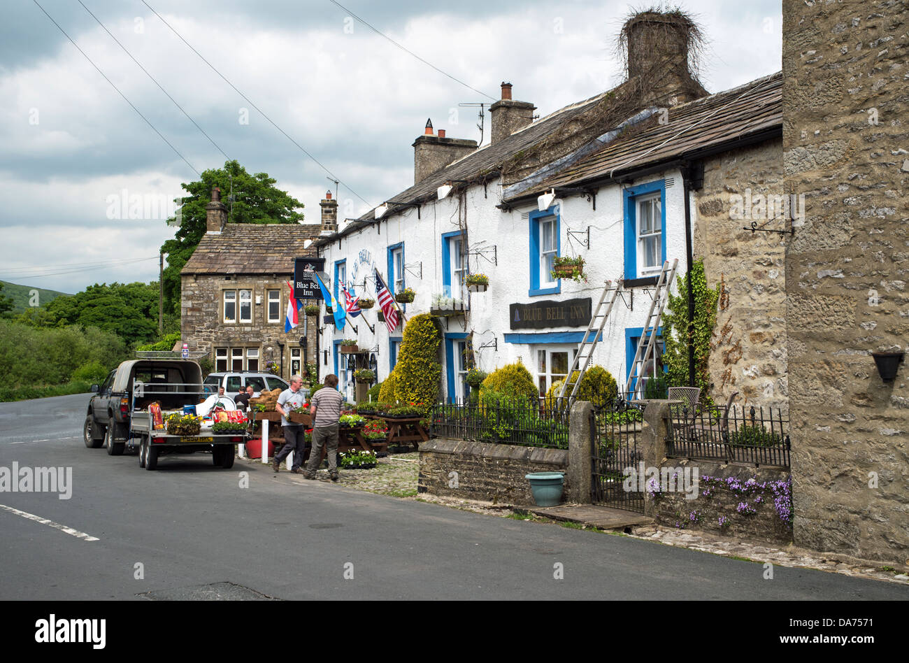 Putting the hanging baskets up in summer at the Blue Bell Inn Kettlewell Wharfedale Yorkshire Dales England Stock Photo