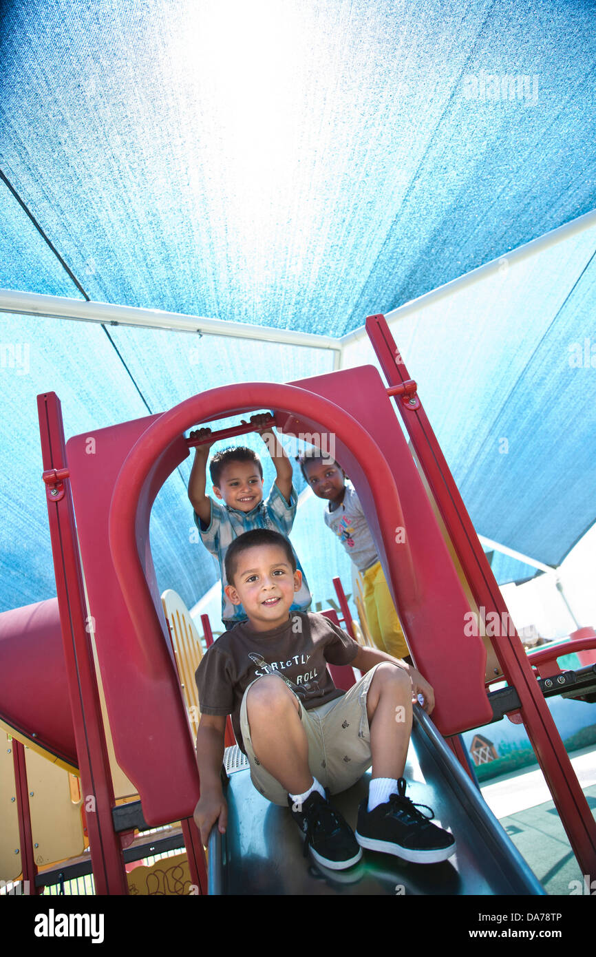 children playing on a playground slide hispanic asain caucasian Stock Photo