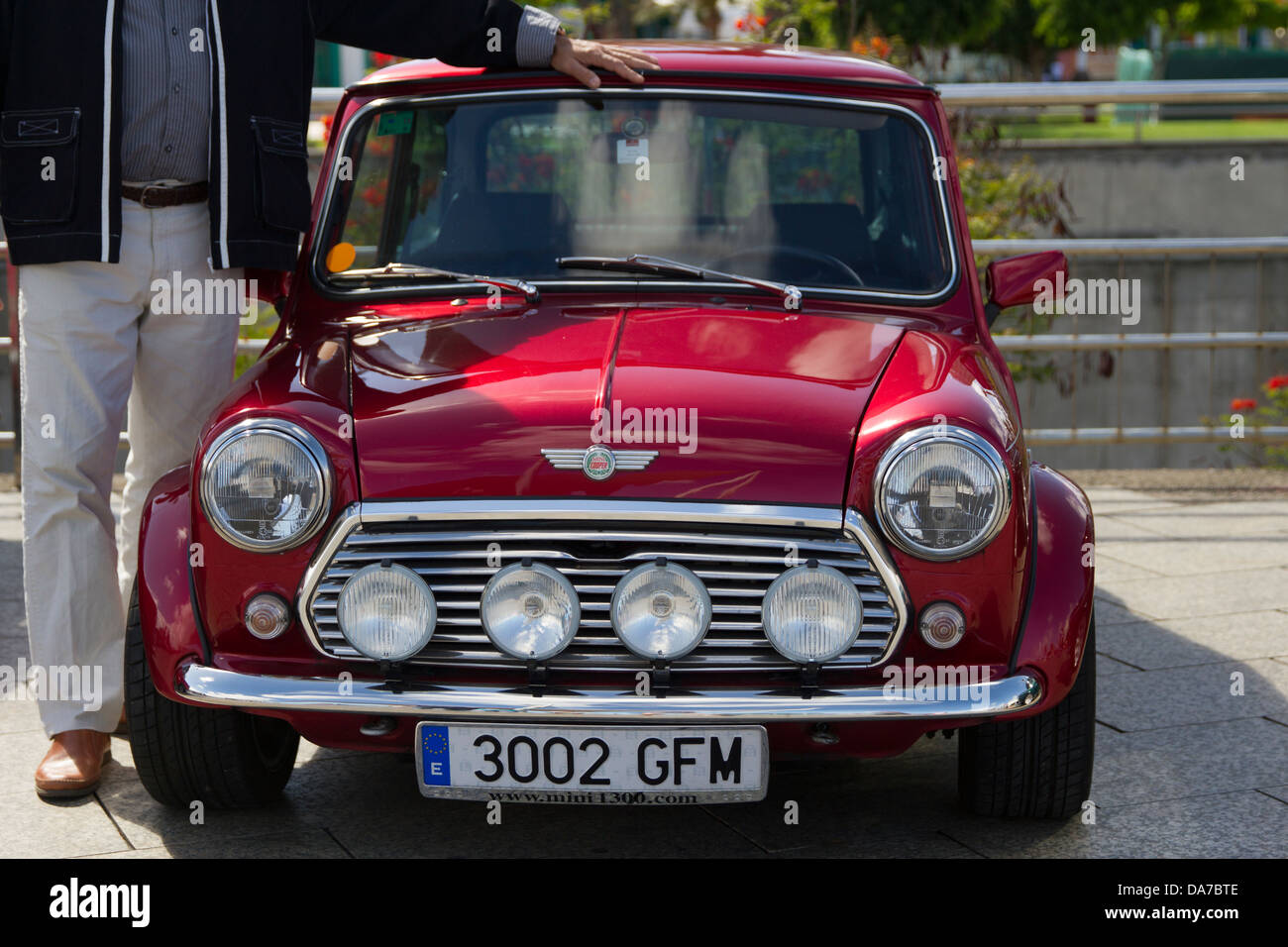 Tall man standing next to a  small Mini Cooper Stock Photo