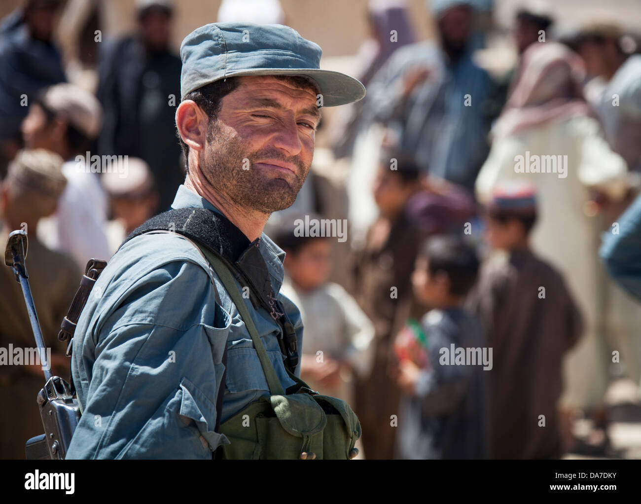 An Afghan National Civil Order Police officer provides security during a distribution of radios and comic books to residents May 26, 2013 in Delaram, Helmand province, Afghanistan. Stock Photo