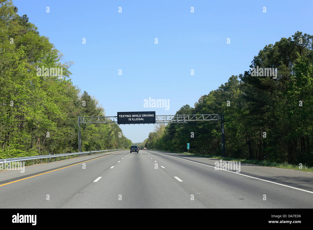 A large highway or road sign message on a US interstate in USA that says Texting while driving is illegal Stock Photo