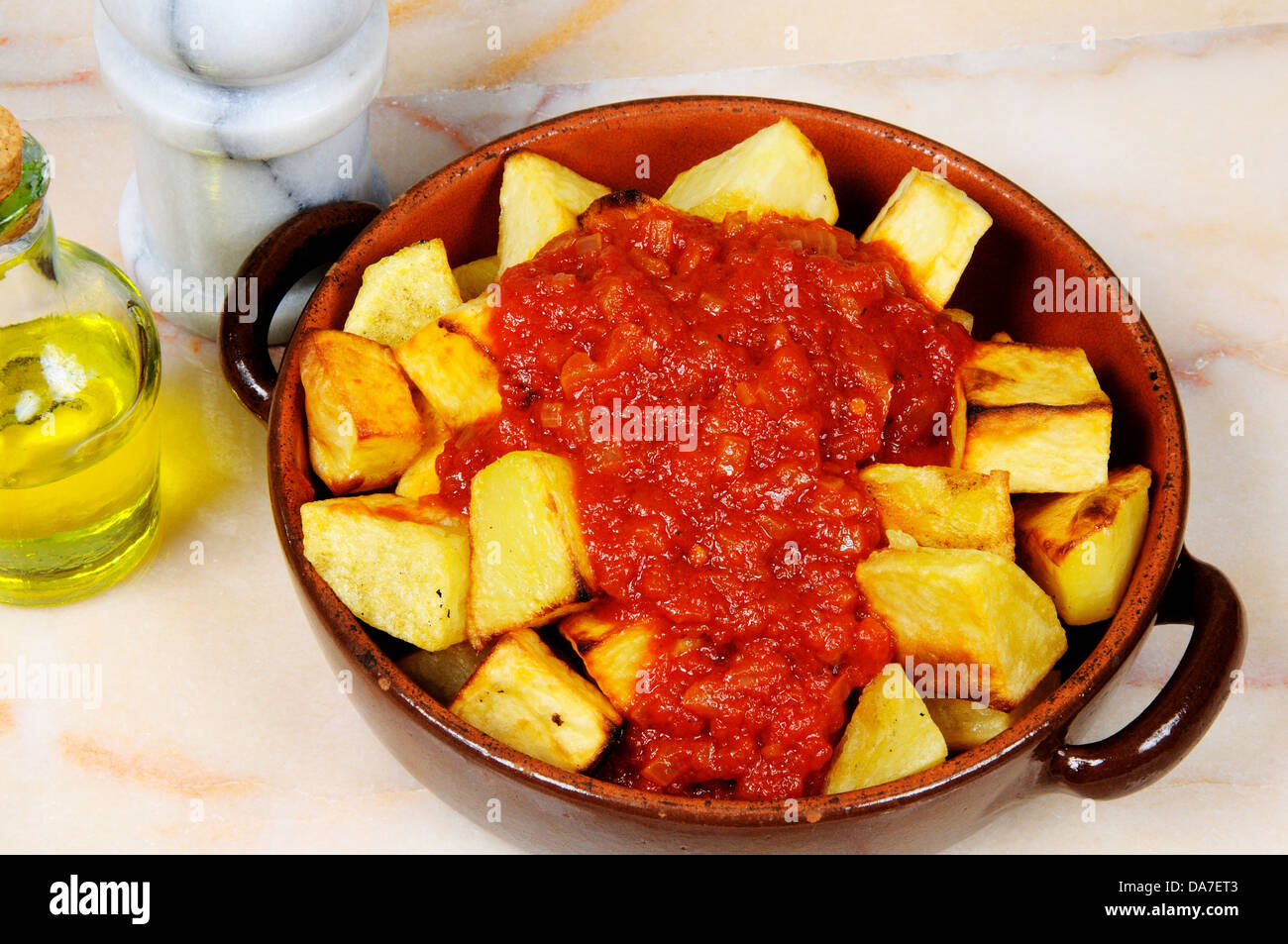 Spanish tapas of Patatas Bravas on a marble table top (Chipped potatoes