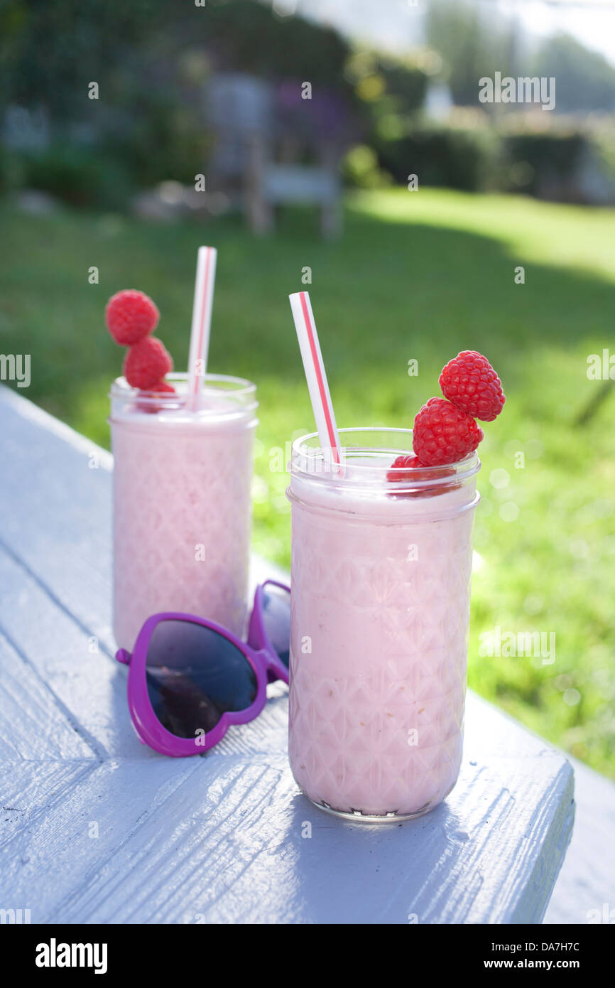 two raspberry smoothies outside on a sunny day Stock Photo