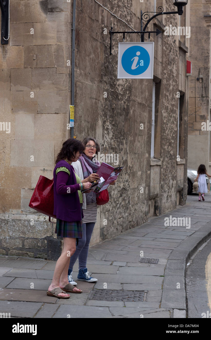 Two females appearing lost, with a tourist information sign close by. Stock Photo