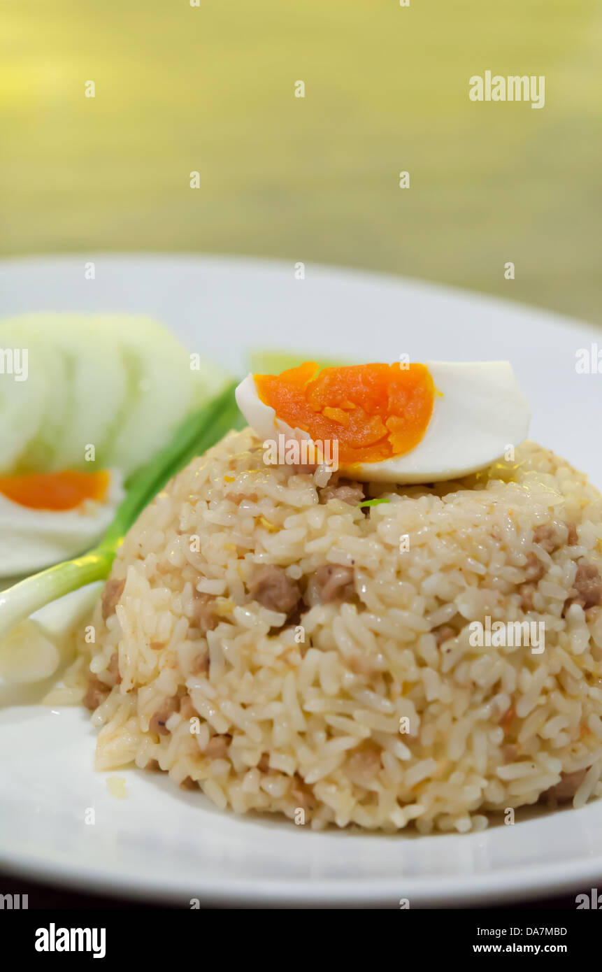close up fried rice with pork and boiled egg served with fresh vegetable on white dish Stock Photo