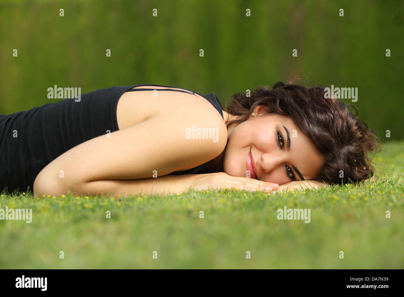 Beautiful woman lying on the grass relaxed and looking at camera with a ...