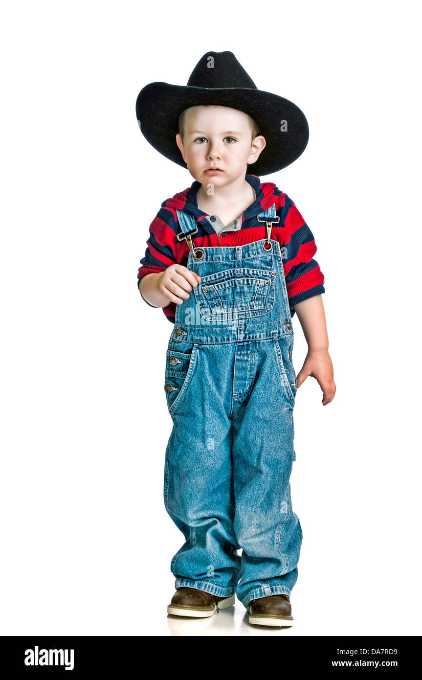 Cute little boy in his cowboy hat and cover-alls with a serious look on