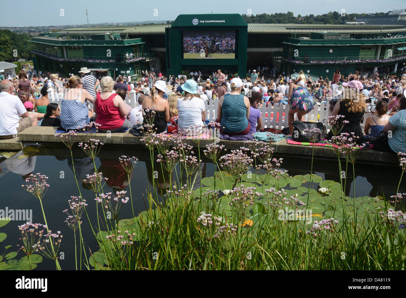 Spectators fans on Henman Hill Murray Mound watching tennis on the big screen Wimbledon with a water feature and lily pads Stock Photo