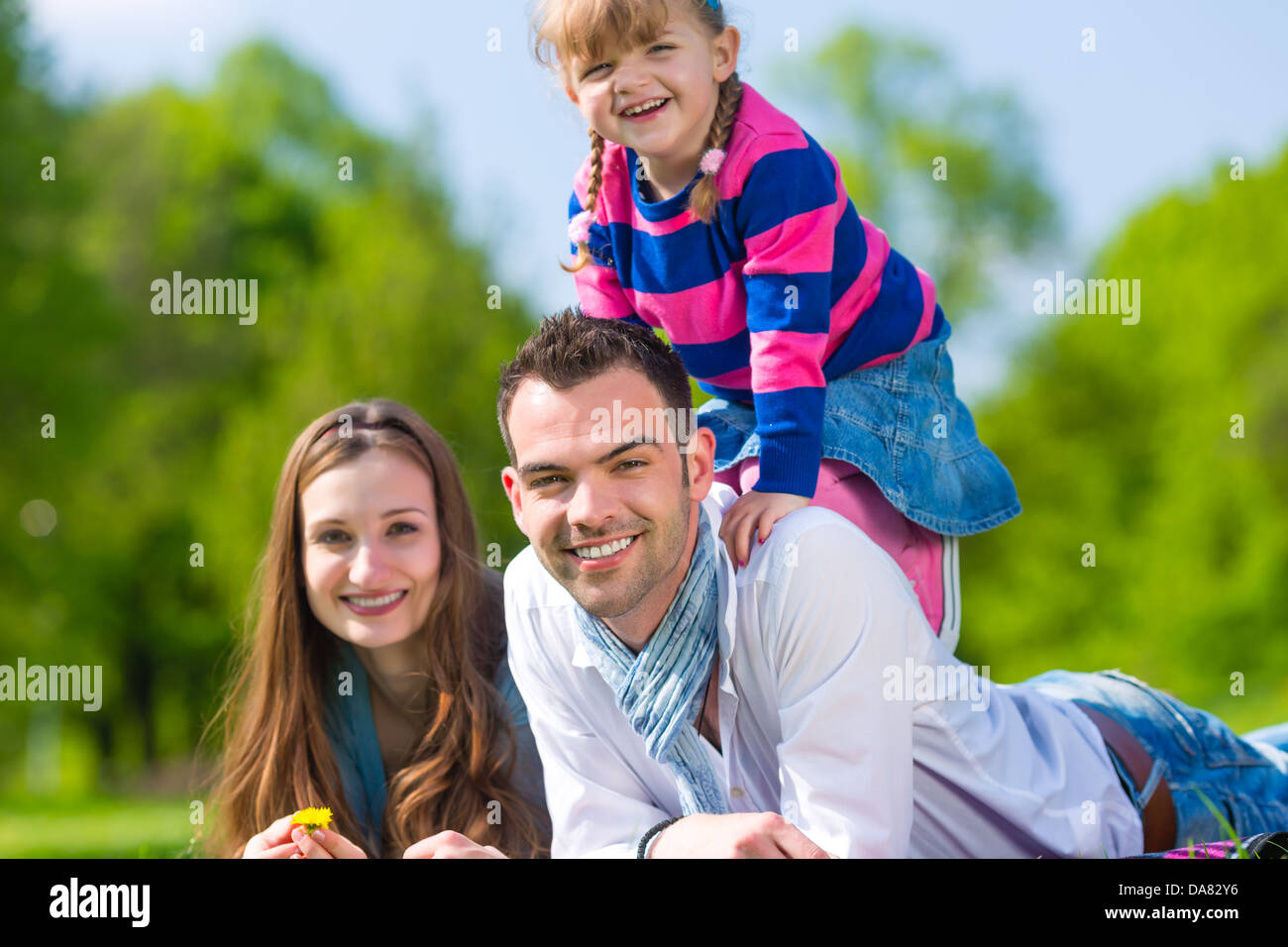 Happy family with daughter sitting in a meadow in summer Stock Photo