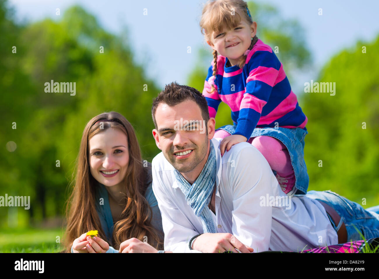 Happy family with daughter sitting in a meadow in summer Stock Photo