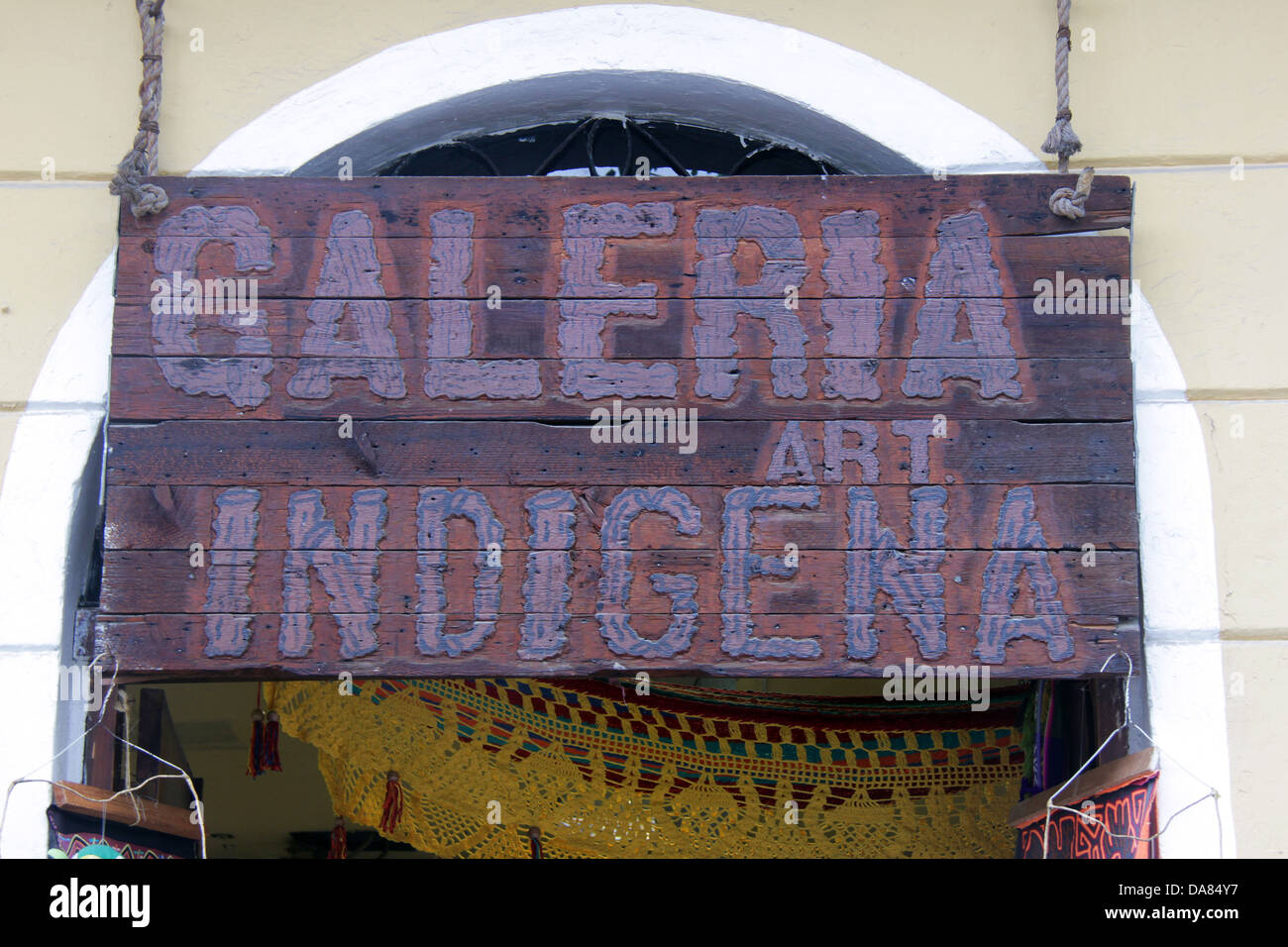 Street sign of a shop written in Spanish with the words indigenous art gallery, made of wood and hanging on a door arch. Stock Photo