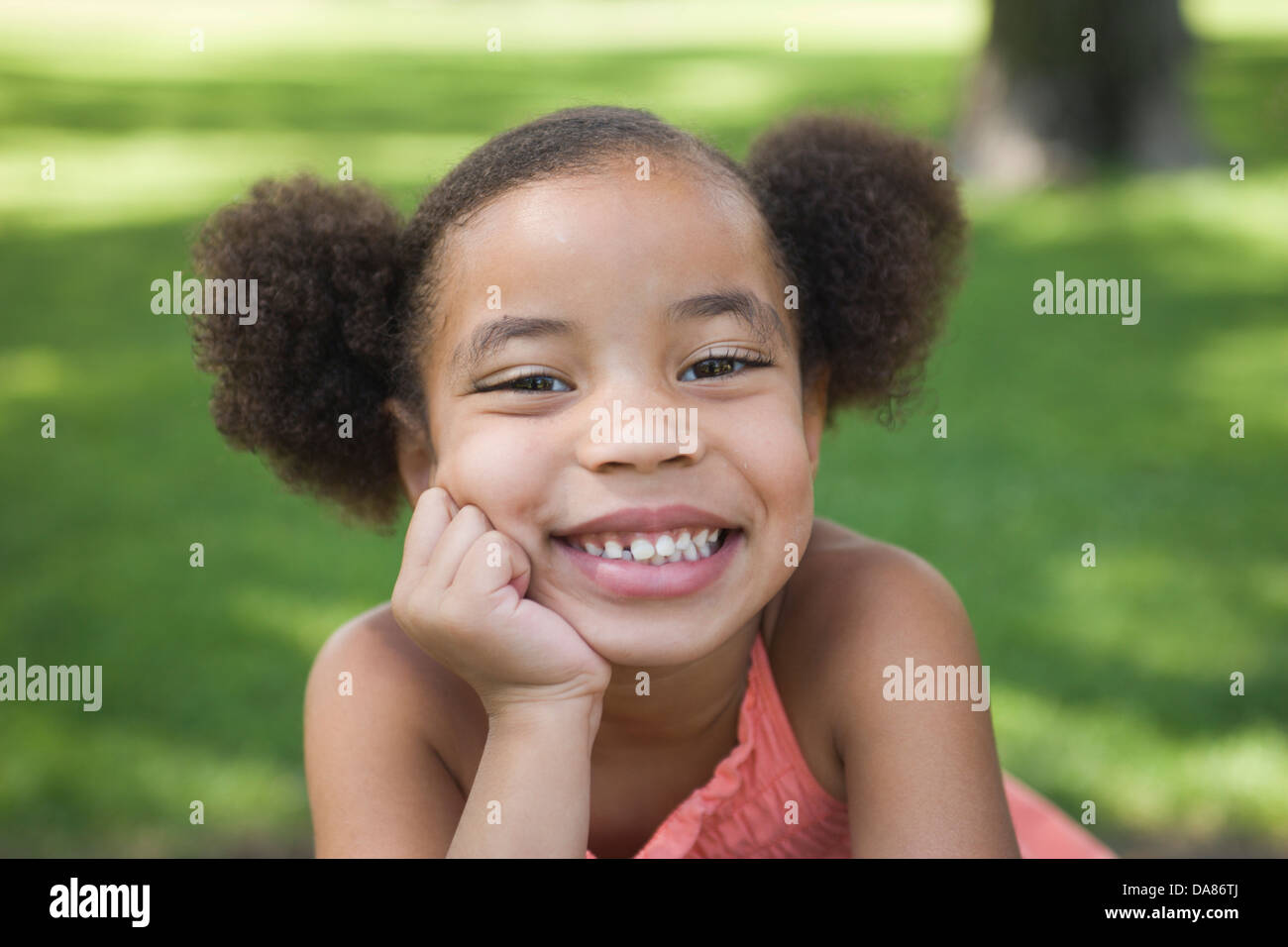 Eight year old African American girl smiles at camera in a park. Stock Photo