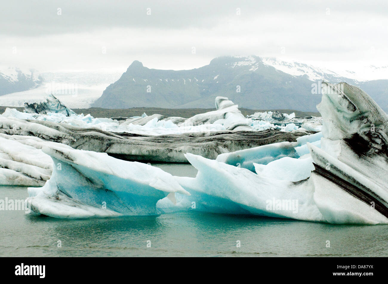 Iceland's snowcapped landscape frames the sculpted ice within the Jökulsárlón lagoon Stock Photo