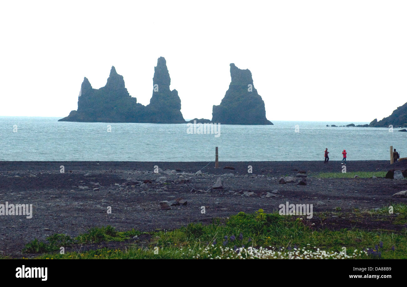 Striking volcanic outcrops off Iceland's south coast at Vik are silhouetted beyond a black lava shore Stock Photo