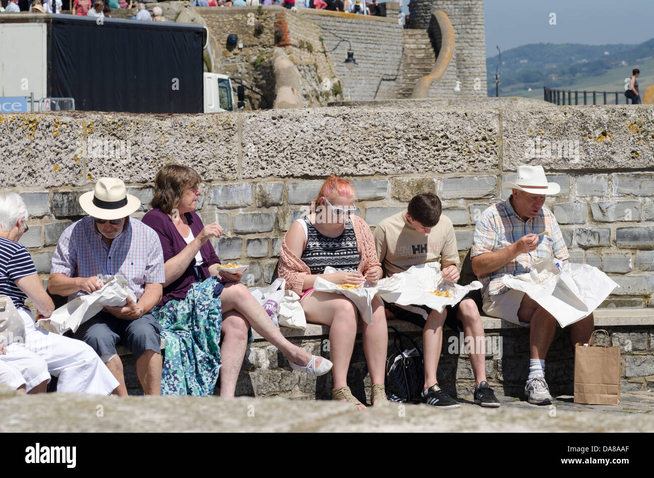 People eating fish and chips by the sea Lyme Regis Dorset UK Stock Photo