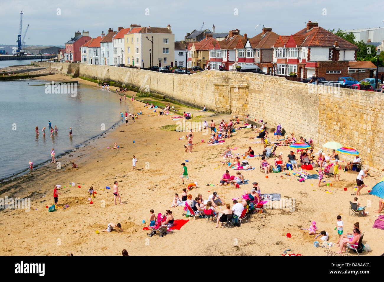 Holidaymakers on the beach by the old medieval sea wall at Hartlepool Headland on a very hot week-end day in Summer 2013 Stock Photo