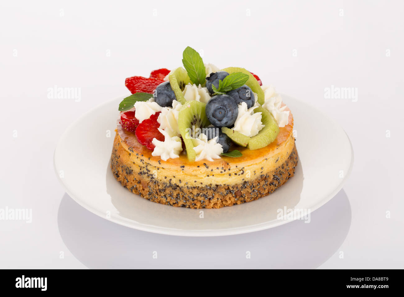Cheesecake with strawberry, blueberry, kiwi and cream on white plate. Stock Photo
