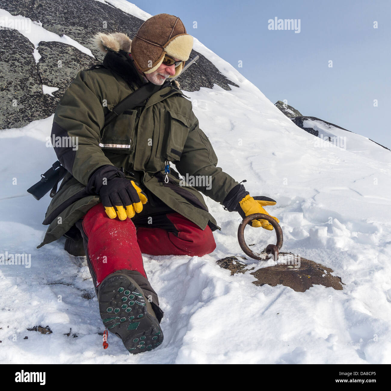 Man dressed in arctic clothing inspects the imbedded metal ring used by the expedition of 1600s explorer Jens Munk Stock Photo
