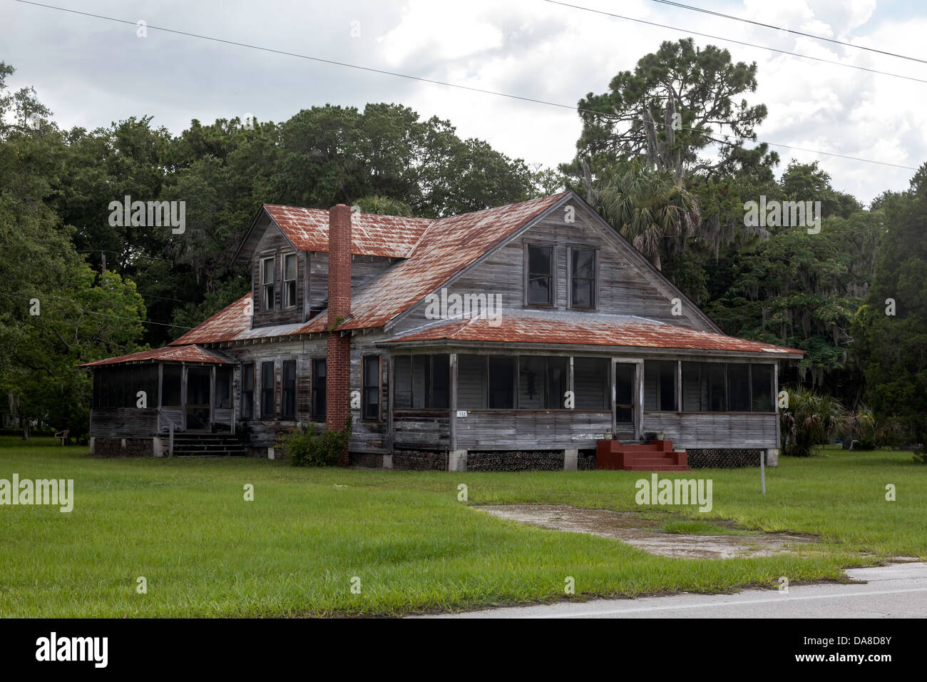 Weathered old Florida farmhouse with red brick chimney, dormer, rusting metal roof and broad verandas in Ingles, Florida. Stock Photo