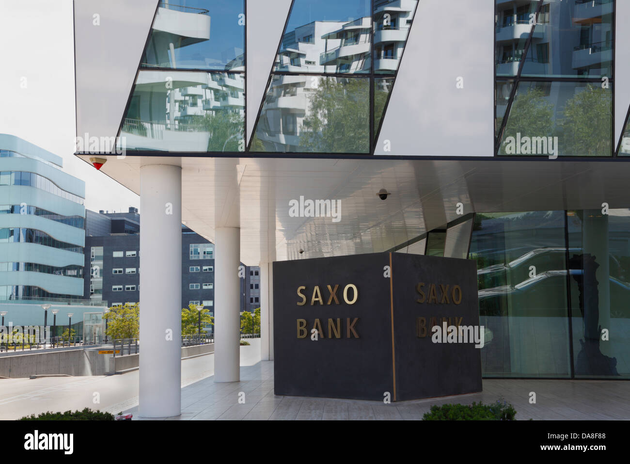 The Saxo Bank building at Tuborg Harbour, Hellerup in Copenhagen, Denmark. Surrounding buildings reflecting in the glass facade. Stock Photo