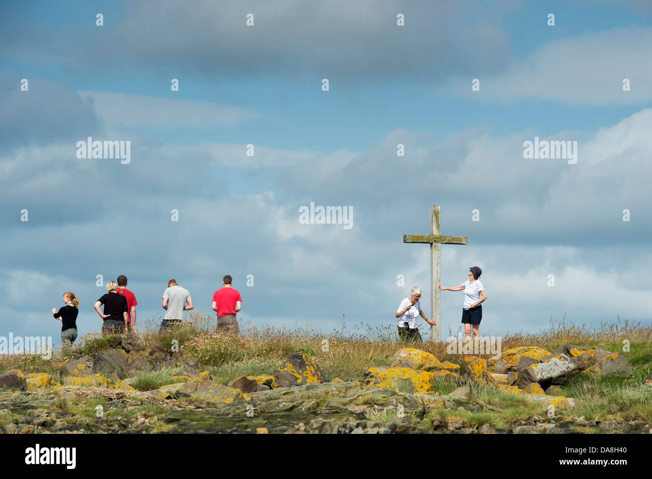People visiting St Cuthbert's Isle wooden cross on Holy Island, Lindisfarne, Northumberland, England Stock Photo