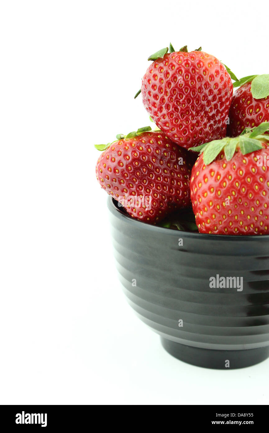 Strawberries into black bowl isolated over white background Stock Photo ...
