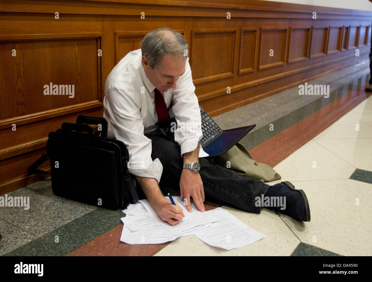 White male sits on floor of Texas Capitol building uses laptop as he writes  notes and prepares testimony for committee hearing Stock Photo - Alamy