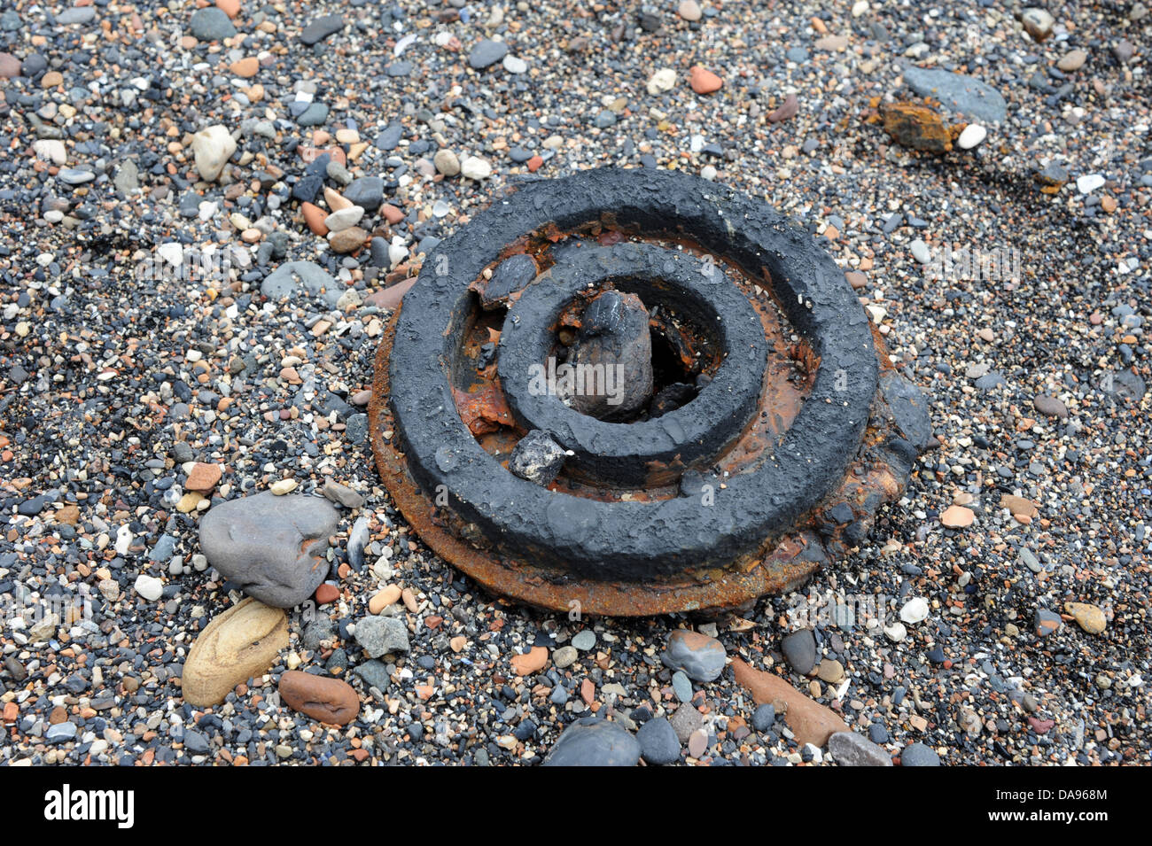 Round metal wheel seen on the beach. Tide debris. Stock Photo