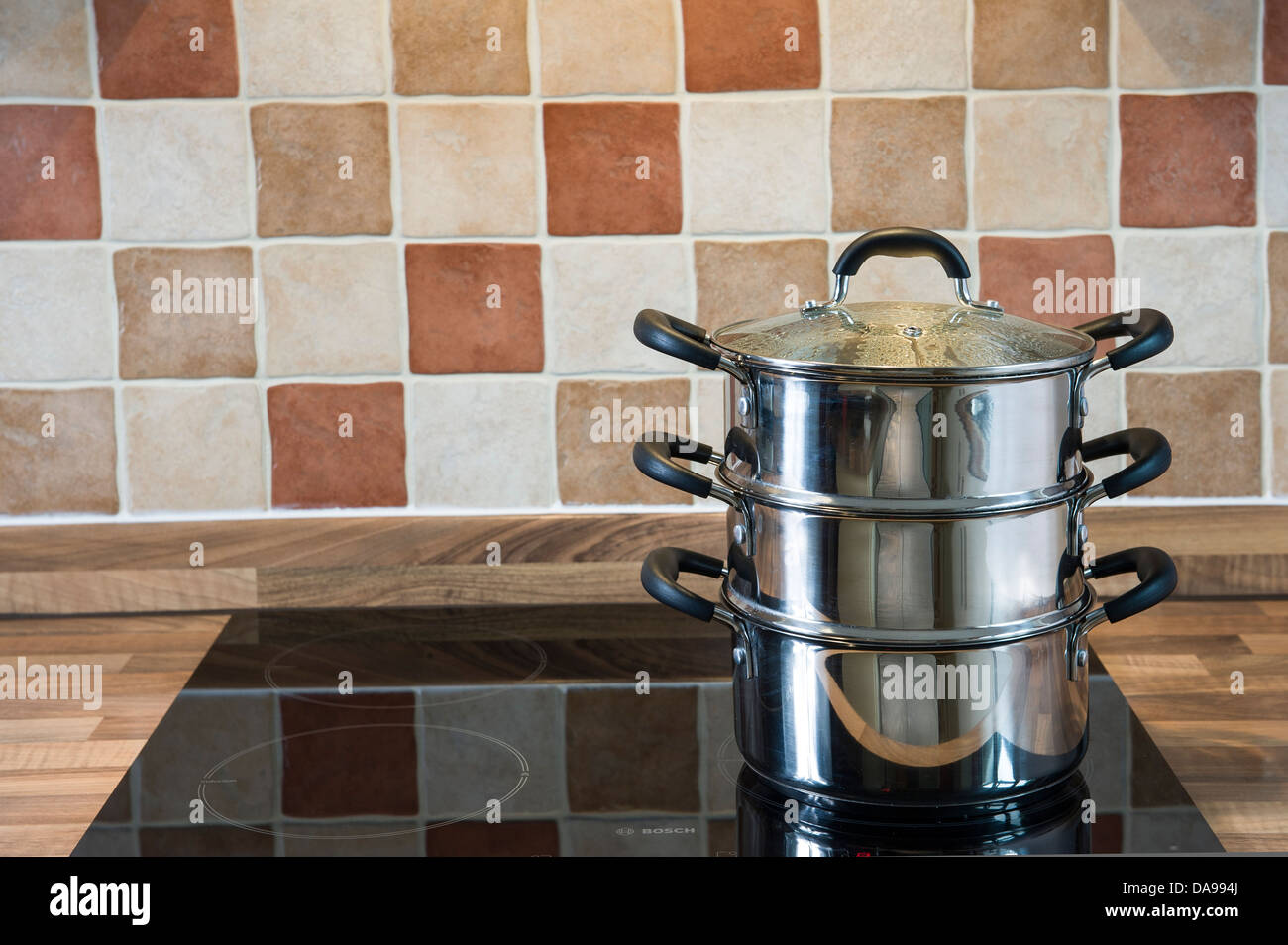 Multi level steamer, stainless steel on an induction hob Stock Photo