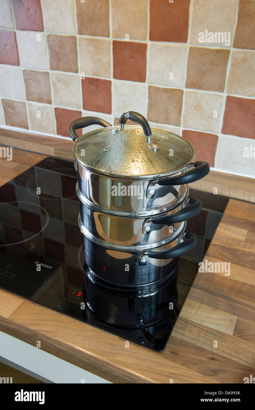 Multi level steamer, stainless steel on an induction hob Stock Photo