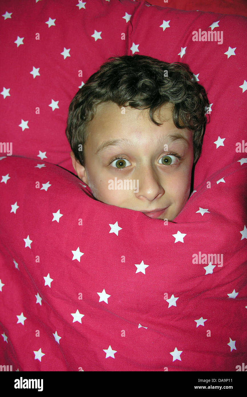 A boy's Cheeky face appears out of duvet Stock Photo Alamy