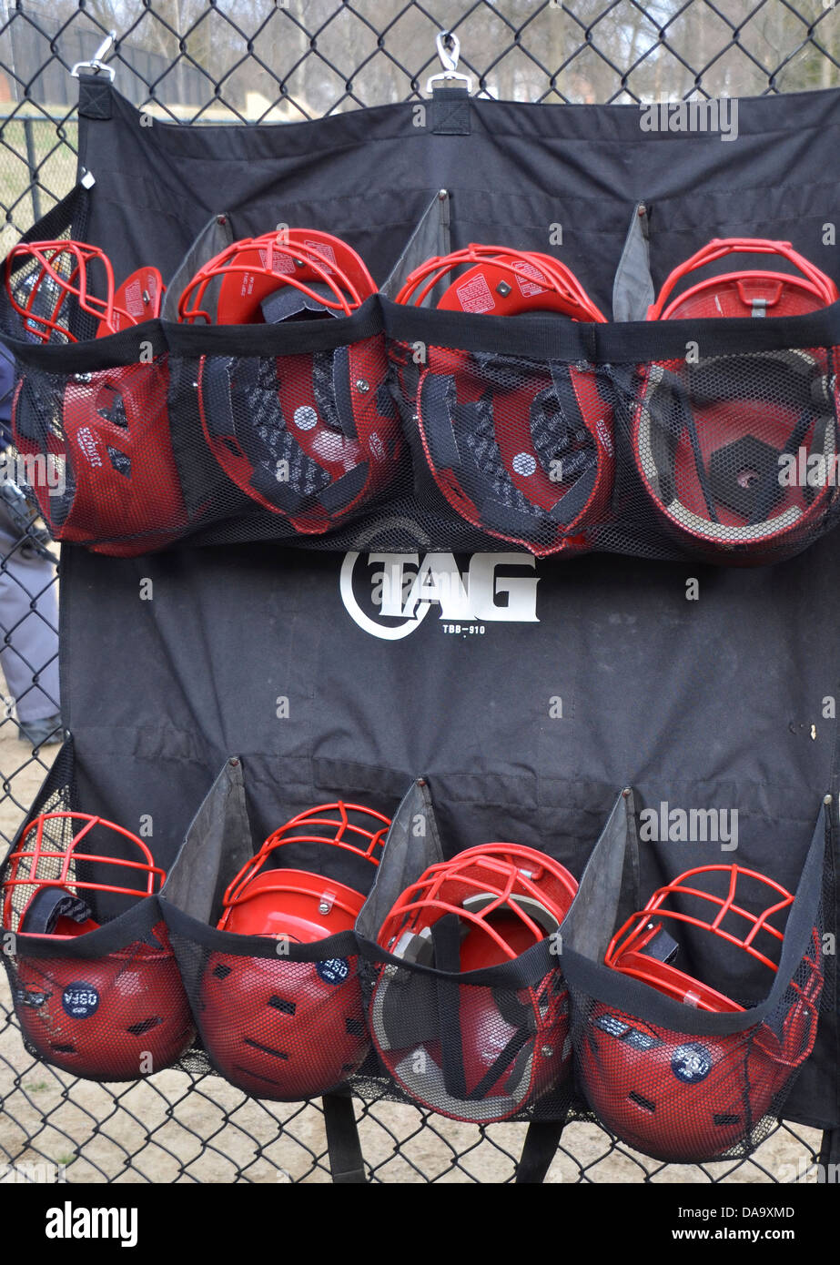 Batting helmets hanging on a backstop Stock Photo