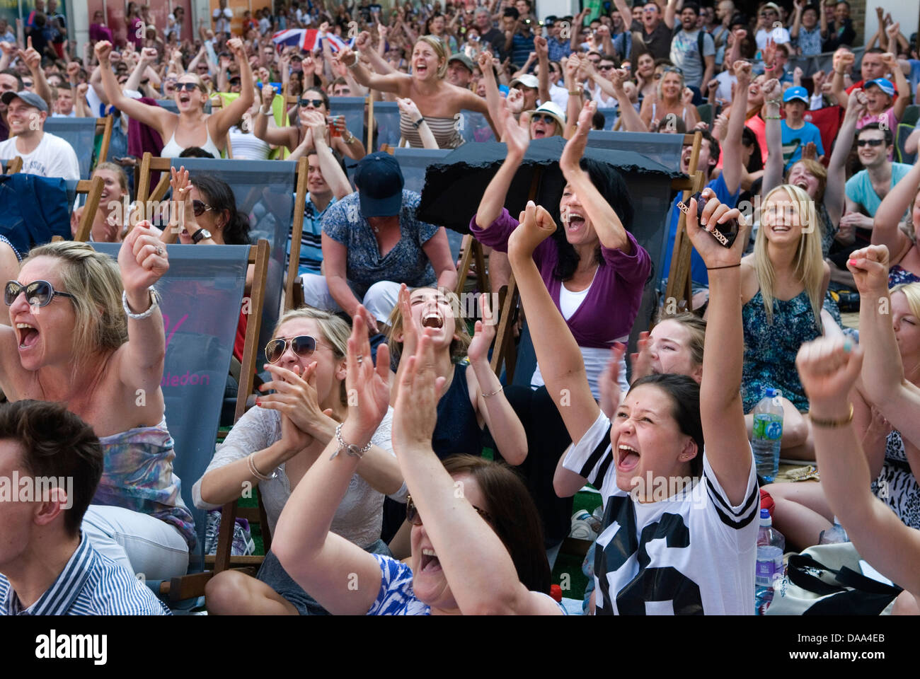 Sports fans young adults, teenage teen girls cheering happy fan watching live sport on outside huge television TV screen. Excited  at the way the game is going, 2013 2010s UK HOMER SYKES Stock Photo
