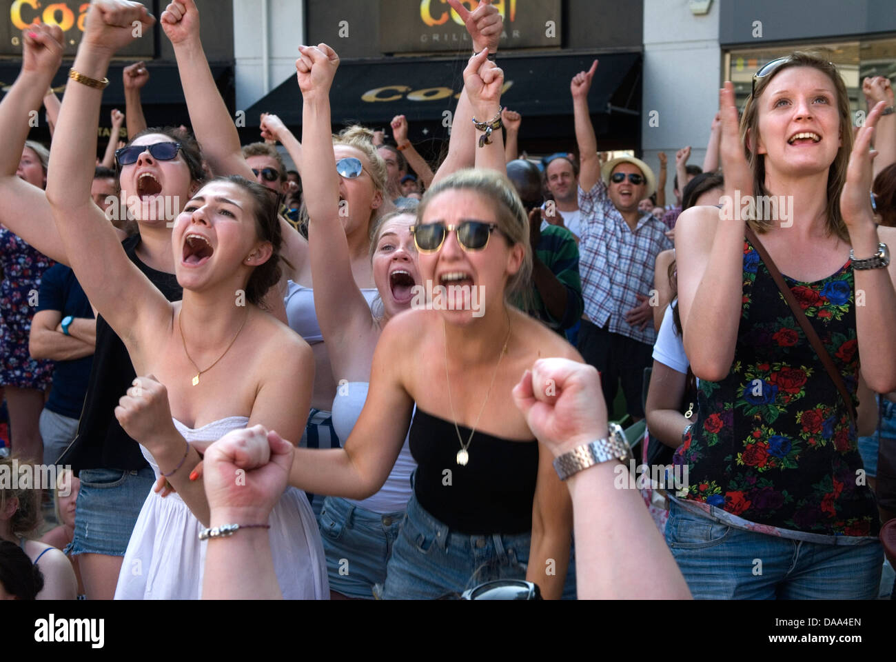 Watching sport on huge TV screen, crowds cheering teen girl sports fans  Wimbledon Town Centre London England  2013 2010s HOMER SYKES Stock Photo