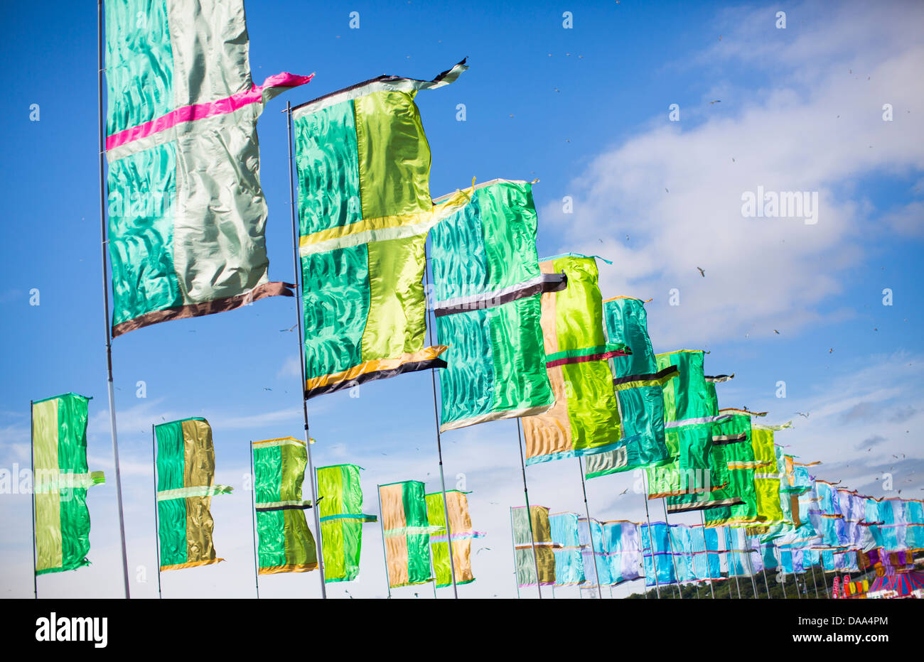Colourful green and blue flags flutter in the wind at Glastonbury Festival 2013. Stock Photo