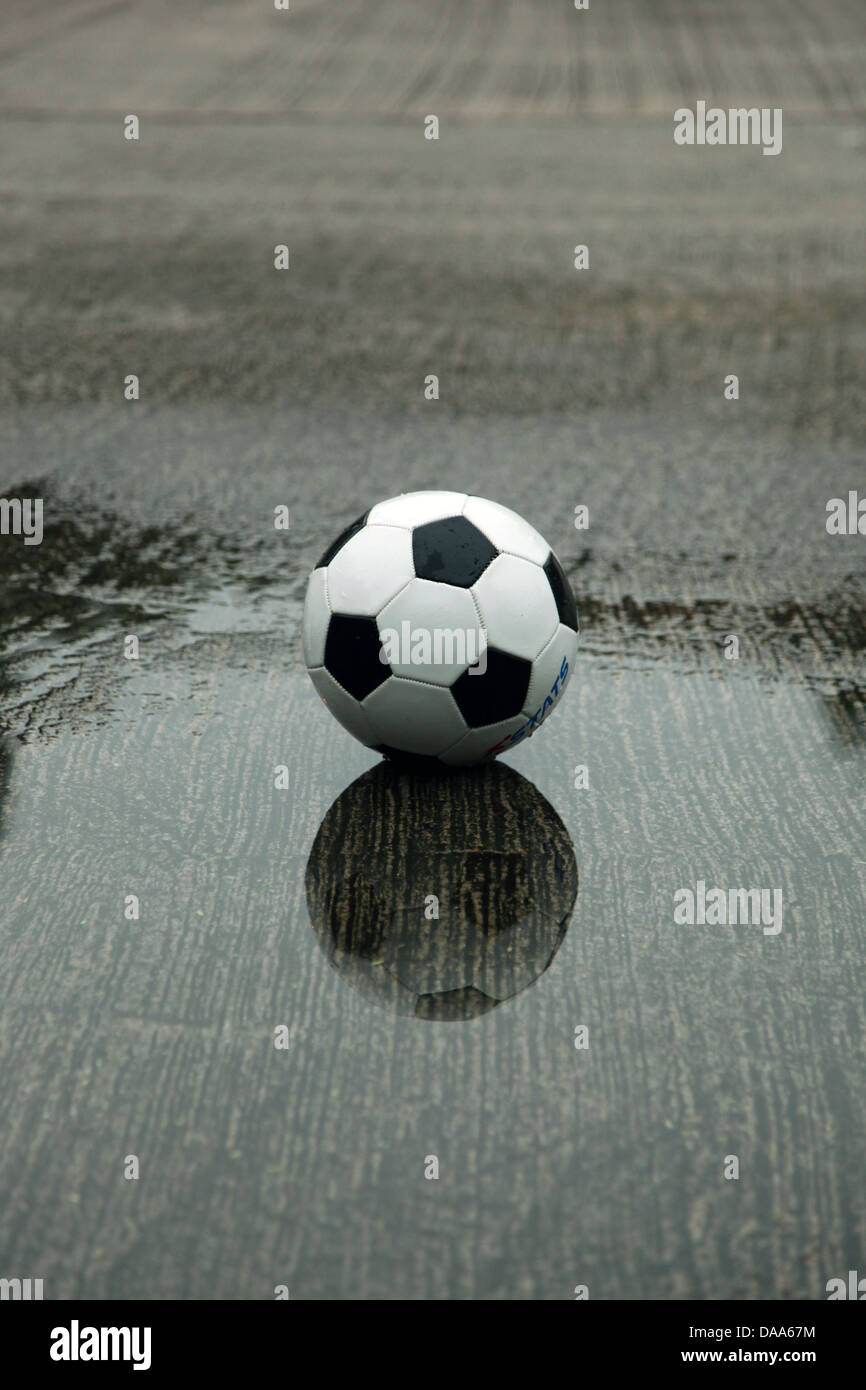it's a photo of a football ball that stands on a wet playground in a