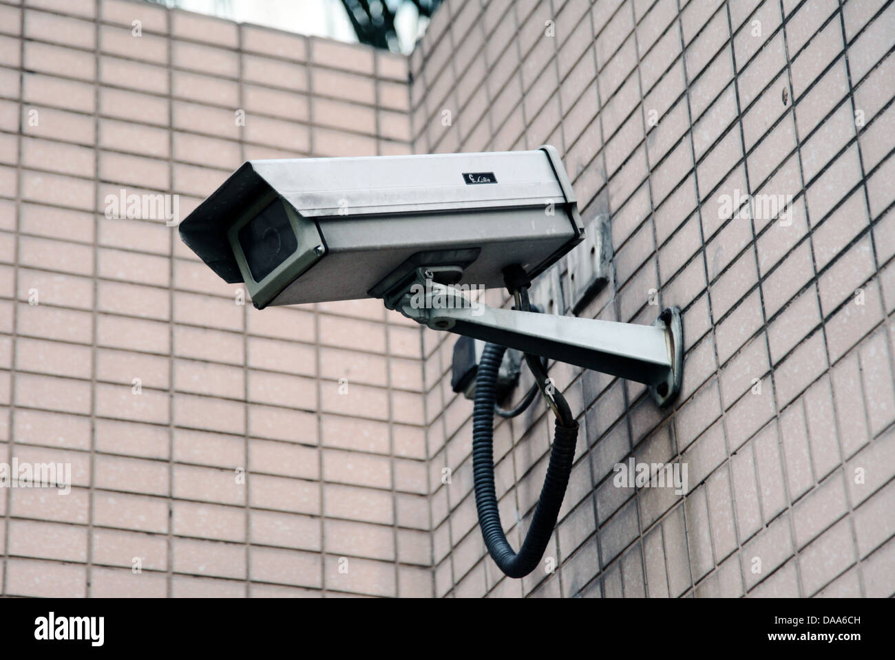 It's a photo of a CCTV camera in the street in the corner of a wall. It's like big brother Stock Photo
