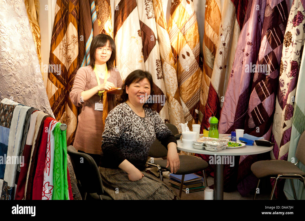 Employees of the Qingdao Sylin Textiles company of China sit at their company's booth at the 'Heimtex' consumer goods and textile trade fair in Frankfurt Main, Germany, 13 January 2011. This year, 2601 exhibitors are present at the fair; 425 companies are from China. Foto: Frank Rumpenhorst Stock Photo