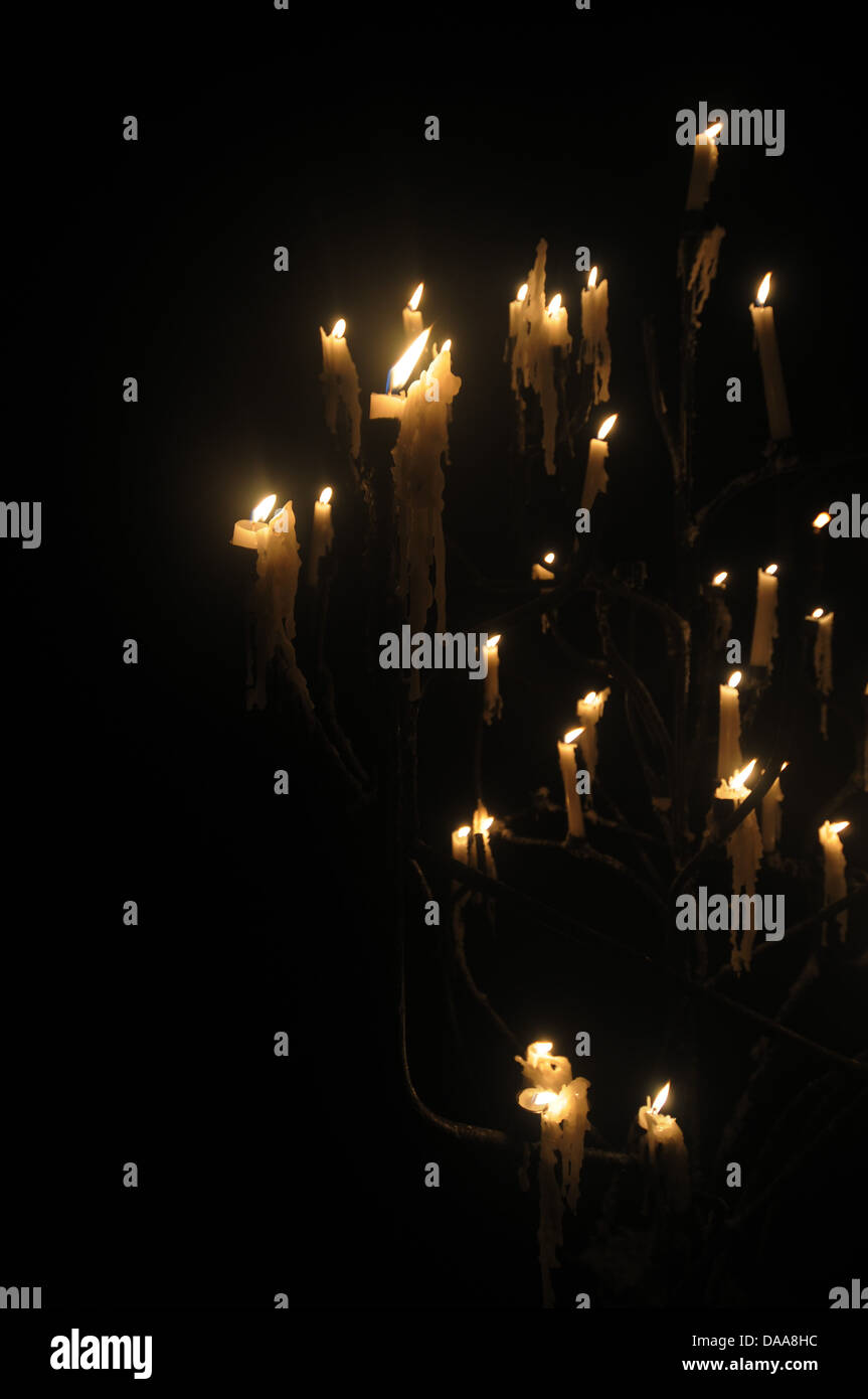 Many candles dripping wax in darkened mysterious candelabra Stock Photo