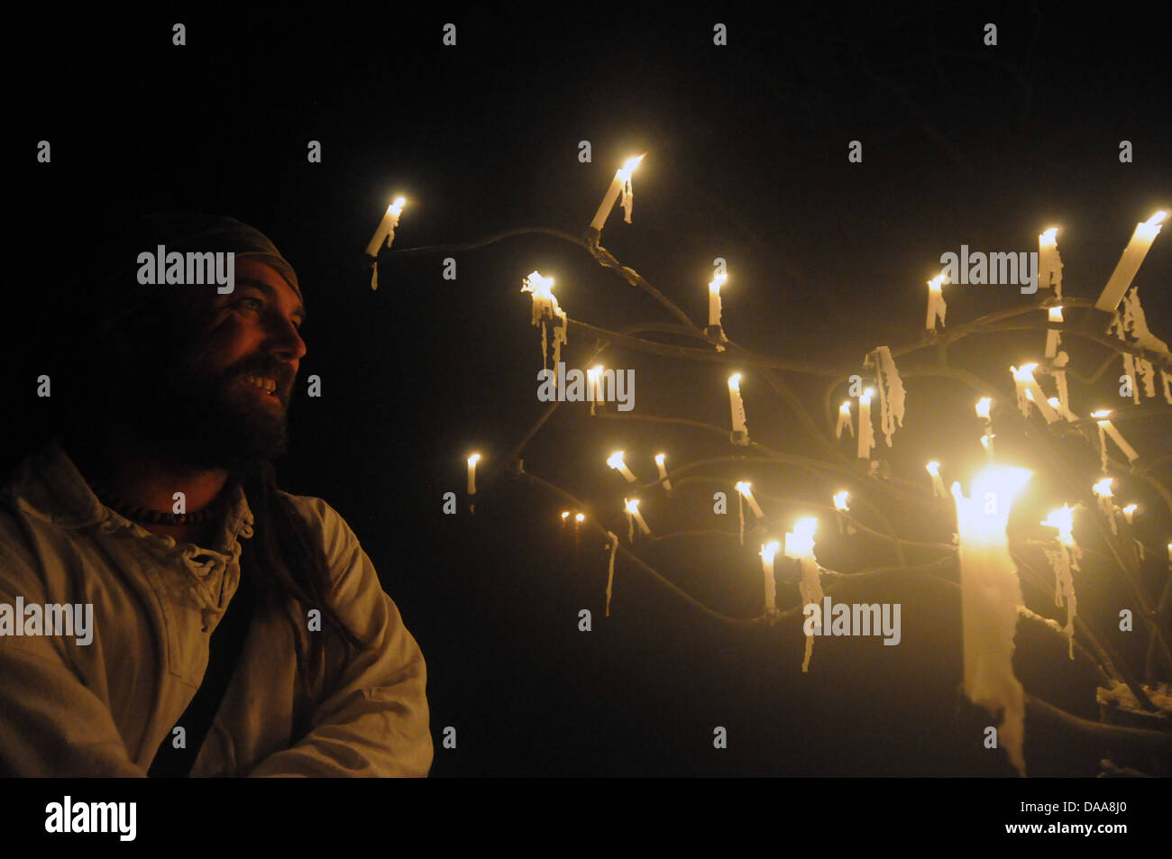 Man with many candles dripping wax in darkened mysterious candelabra Stock Photo