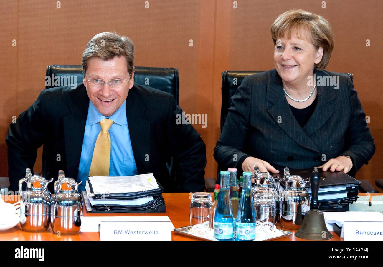 Foreign Secretary and Vice-Chancellor Guido Westerwelle (L) and German Chancellor Angela Merkel (R) are sitting at a table at the cebinet meeting at the chancellor's office on 19. January 2011 to discuss Mrs Aigner's, the Minister of Agriculture, plans and suggestions for a more effective protection of consumers from poisoned food. Aigner wants to establsih more rigorous controls a Stock Photo