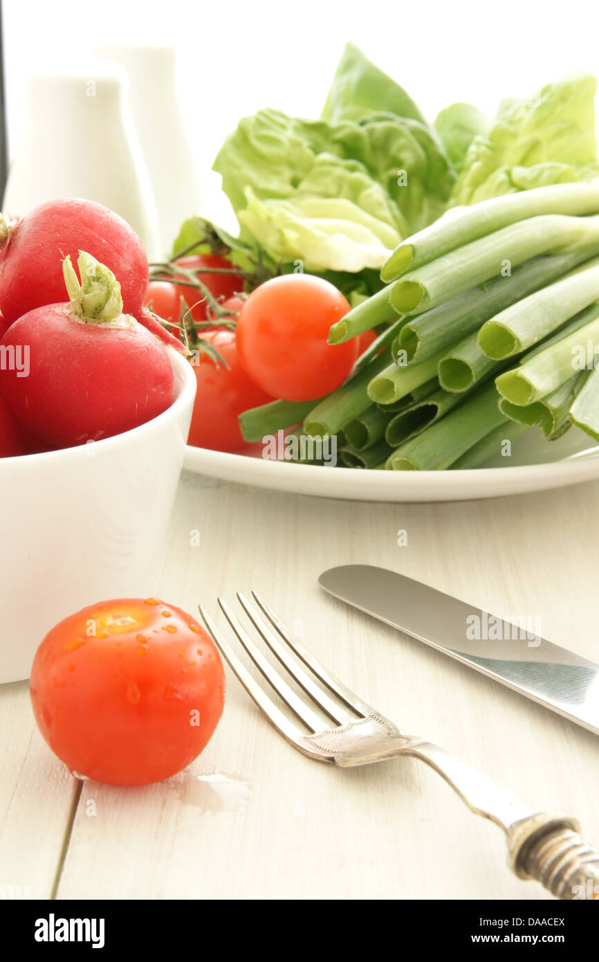 A summery lunch time salad setting with tomatoes lettuce spring onions and radishes Stock Photo