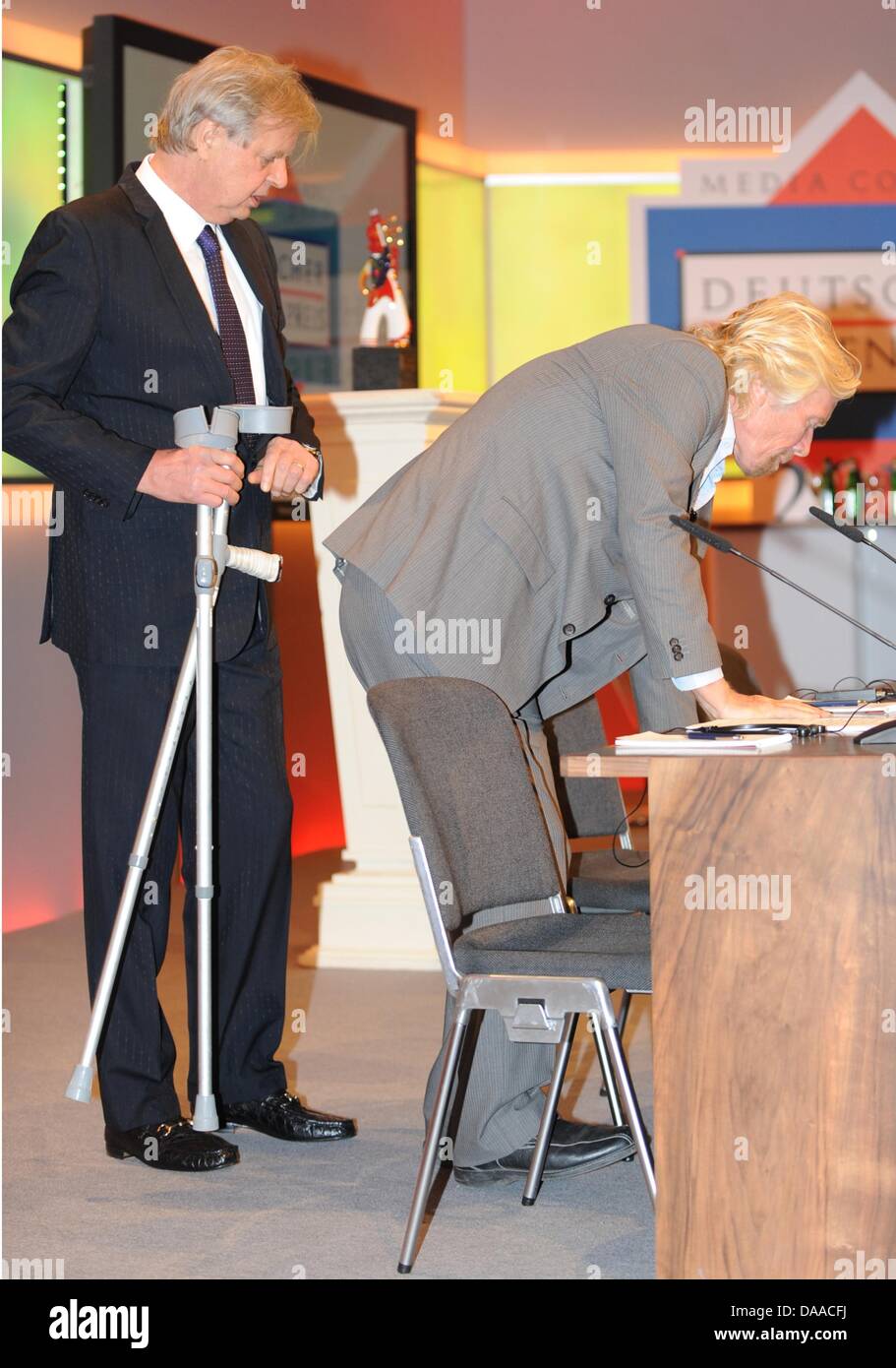 British enterpriser and billionaire Richard Branson (r)arrives for the award ceremony of the German Media Prize 2010 together with Karlheinz Koegel (l)at the Congress Center of Baden Baden, Germany, 24 January 2011. Despite his cruciate ligament rupture, he showed up on crutches to receive his prize. Since 1992, the German Media Prize is awarded to a public figure, who has, accordi Stock Photo