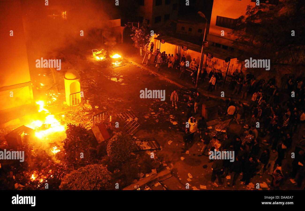 Demonstranten versammeln sich in der Nacht zum Samstag (29.01.2011) an einem brennenden Haus in Kairo. Die Plünderungen und Ausschreitungen in der ägyptischen Hauptstadt Kairo sind auch am Samstagmorgen weitergegangen. Dies berichteten Augenzeugen. In zwei Kairoer Vierteln seien aus gestürmten Polizeiwachen Häftlinge befreit worden. Auch in Alexandria kam es nach Angaben des arabis Stock Photo