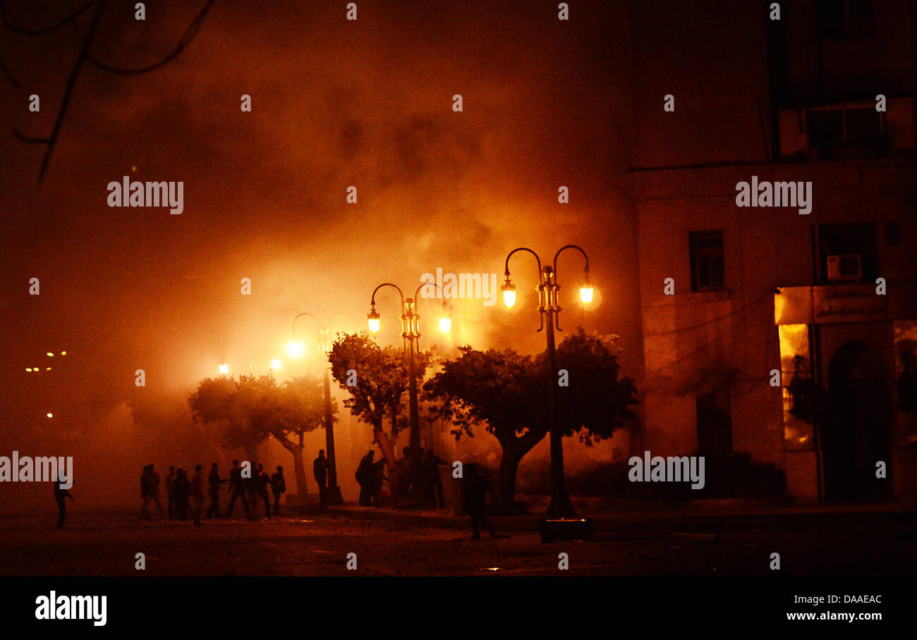 Demonstranten greifen in der Nacht zum Samstag (29.01.2011) ein bereits brennendes Gebäude in Kairo an. Die Plünderungen und Ausschreitungen in der ägyptischen Hauptstadt Kairo sind auch am Samstagmorgen weitergegangen. Dies berichteten Augenzeugen. In zwei Kairoer Vierteln seien aus gestürmten Polizeiwachen Häftlinge befreit worden. Auch in Alexandria kam es nach Angaben des arabi Stock Photo