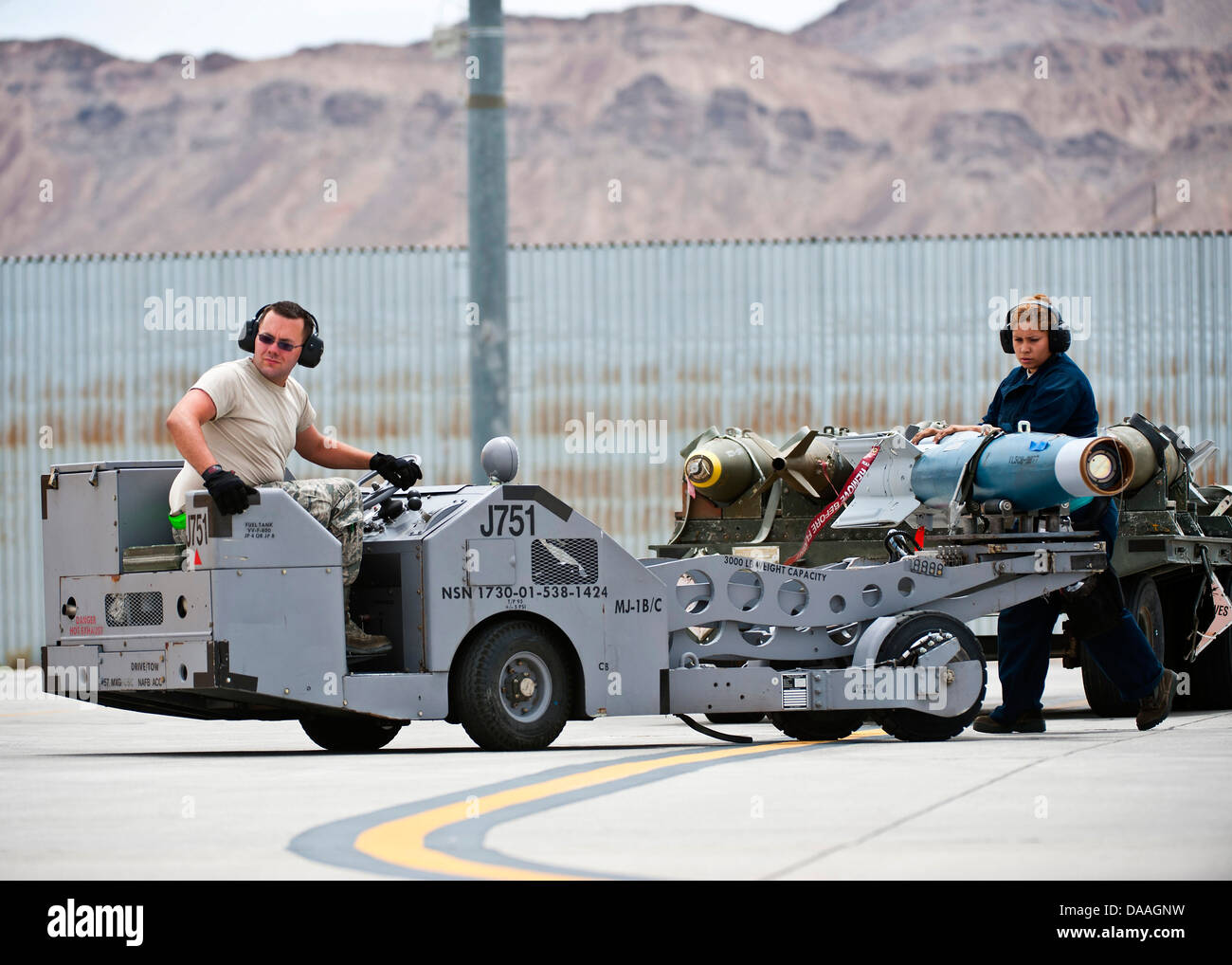 Airman 1st Class James Haddock and Staff Sgt. Lorena Hodge, 4th Aircraft Maintenance Squadron aircraft armament systems technicians, Seymour Johnson Air Force Base, N.C., transport a GBU-20 inert bomb during Green Flag-West 13-5 June 24, 2013, at Nellis A Stock Photo