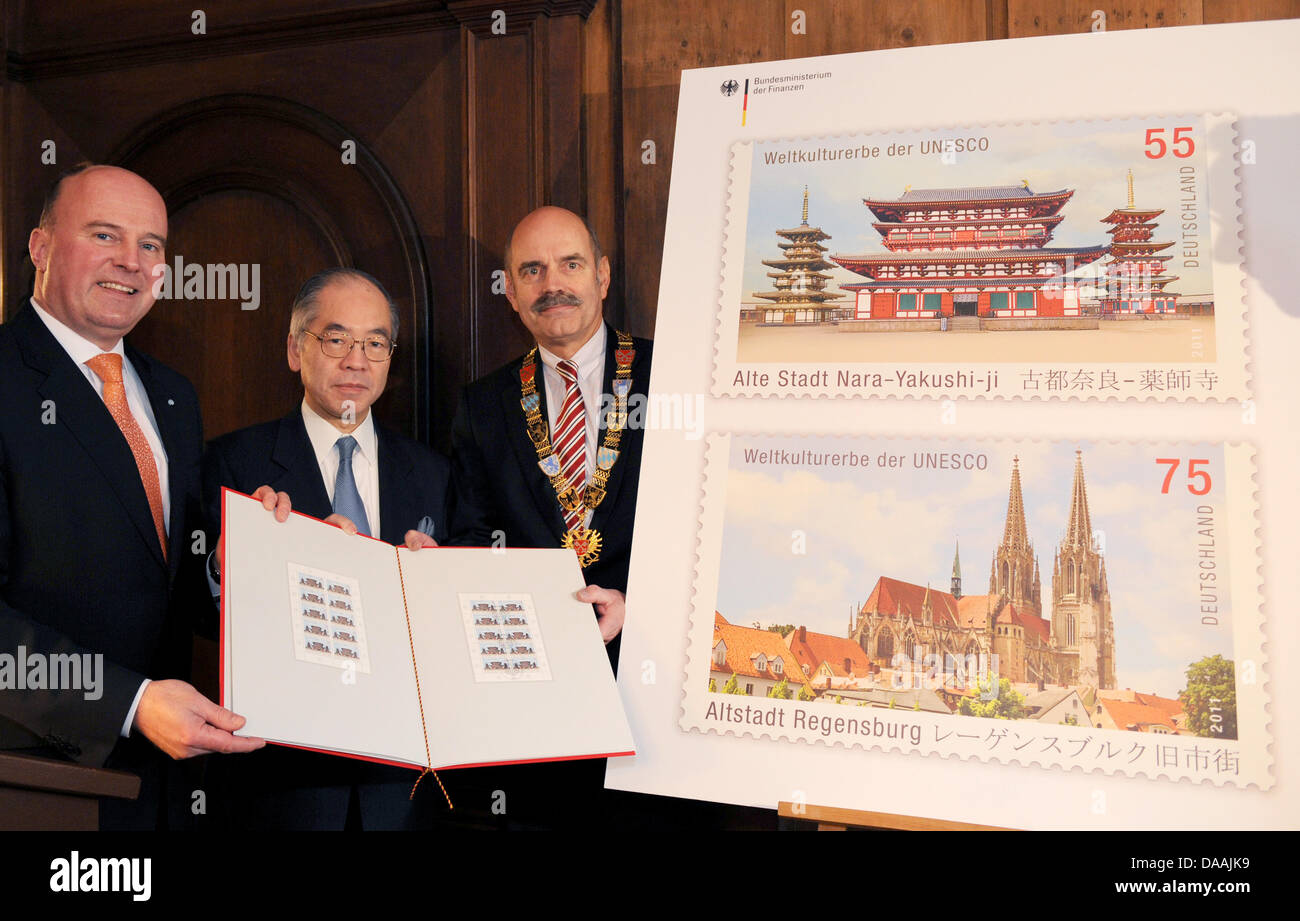 The Paliamentary State Secretary of the Federal Ministry of Finance, Harmut Koschyk (CSU, L-R) the Japanese Ambassador to Germany, Takahiro Shinyo, and the Mayor of Regensburg, Hans Schaidinger, stand next to an enlarged image of a postage stamp depicting the Regensburg Cathedral (below) and the Yakushi-ji Temple in Nara, Japan in Regensburg, Germany, 04 February 2011.  The 75 cent Stock Photo