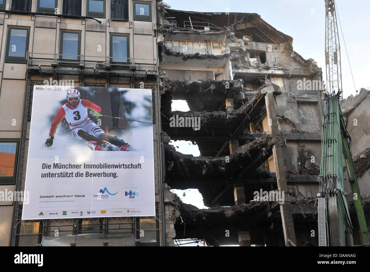 A large advertisement with the caption 'Munich real estate bank supports the German application for hosting the Olympic Games in 2018' hangs on a house that is in the process of demolition in Munich, Germany, 4 February 2011. Is this supposed to be ironic? Photo: Peter Kneffel Stock Photo